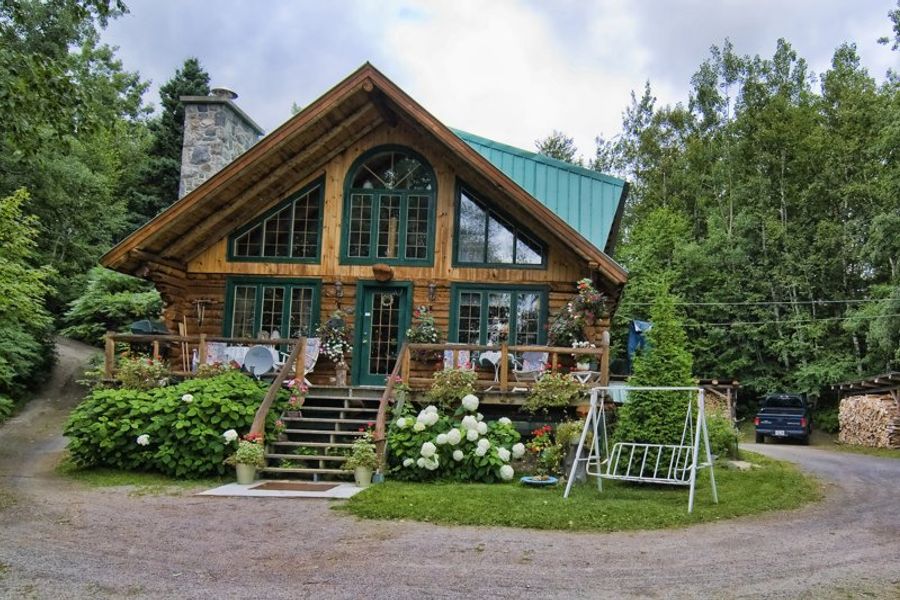 Charmante maison en bois entourée de verdure, typique de la région de Tadoussac.
