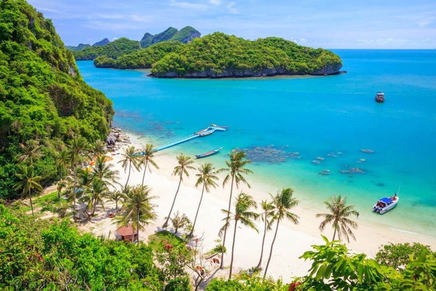 Plage de sable blanc entourée de falaises calcaires et palmiers à Koh Samui