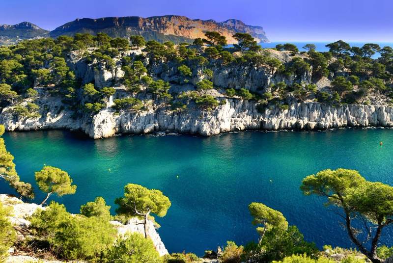 Vue spectaculaire d'une calanque méditerranéenne aux eaux turquoise entourée de falaises rocheuses et de pins, dans le sud de la France.