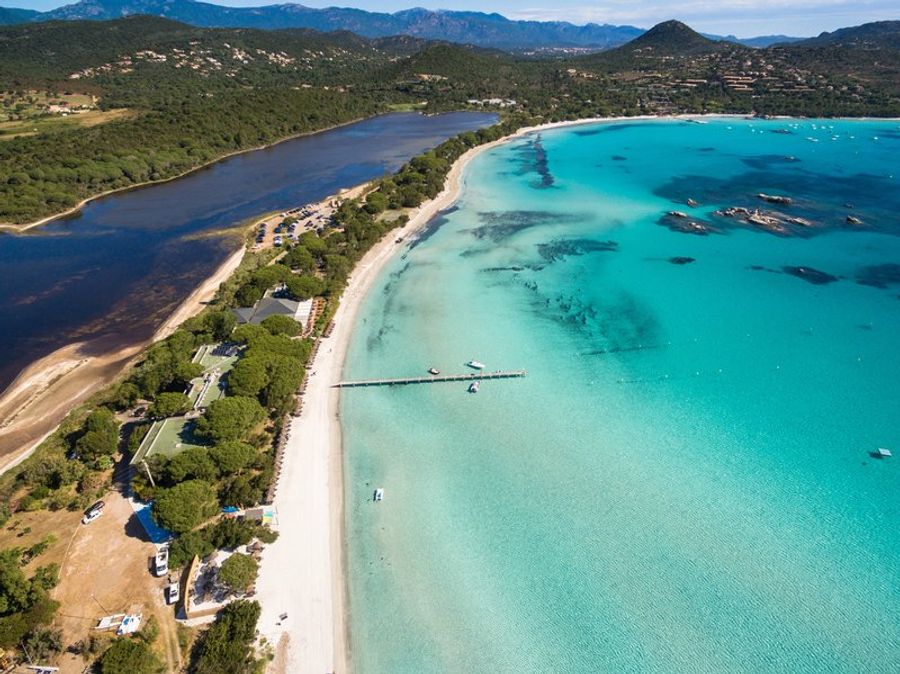 Vue aérienne de la plage de Santa Giulia en Corse, avec son sable blanc, ses eaux turquoise et son environnement naturel préservé.