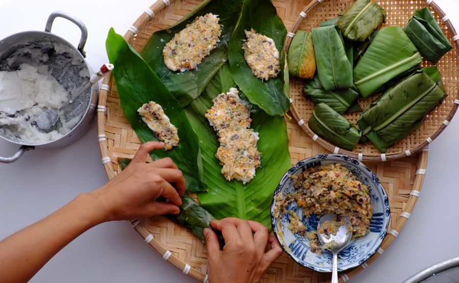 Préparation de plats traditionnels balinais, avec des feuilles de bananier, des ingrédients frais et des mains en action.