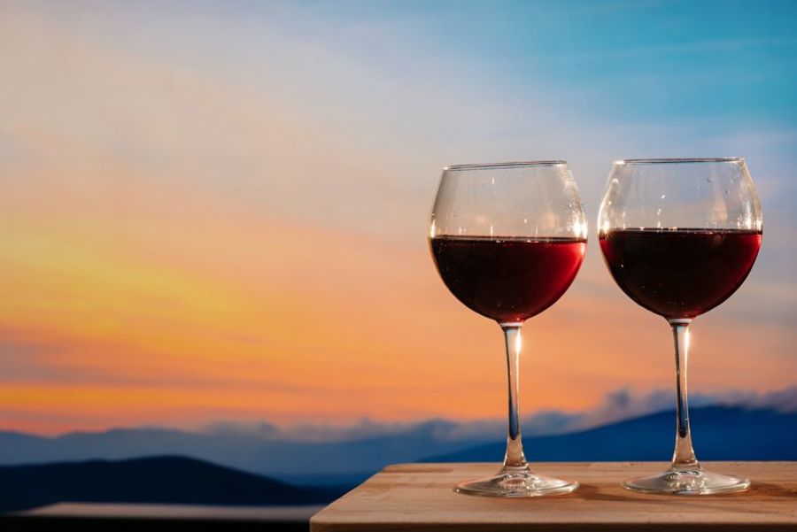 Deux verres de vin rouge sur une table en bois avec un coucher de soleil en arrière-plan à Palma de Majorque.