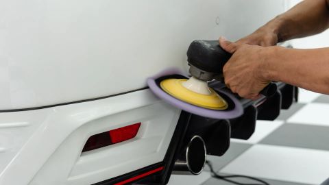 Polermaskin på stötfångaren på en vit bil
