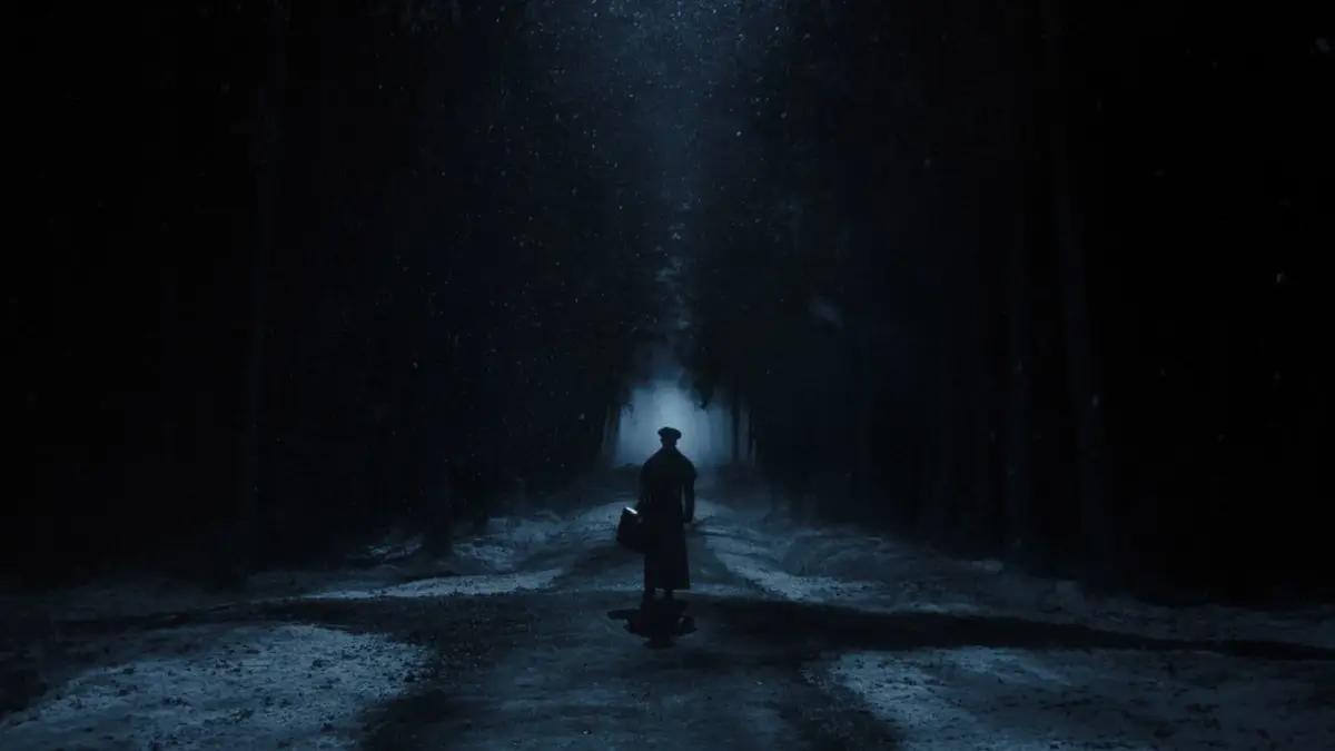 a figure standing at a dark foggy crossroads in the the woods