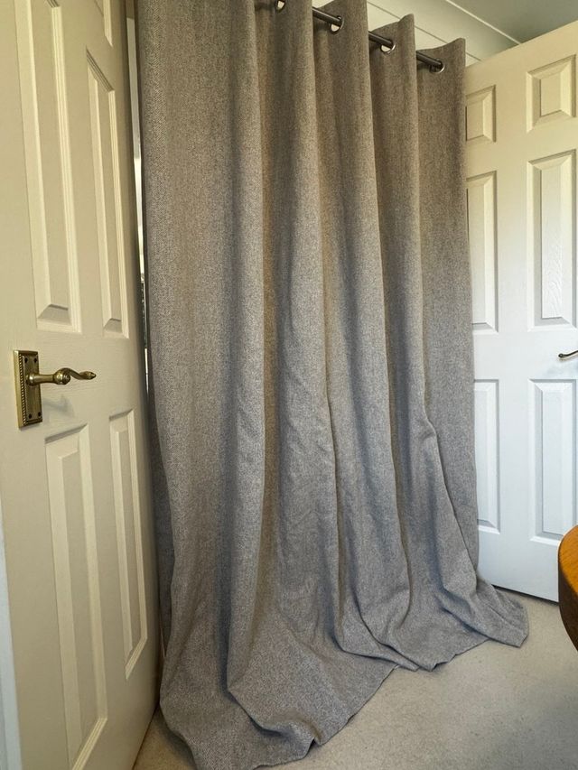 Long grey curtain pooling on a beige carpet, before