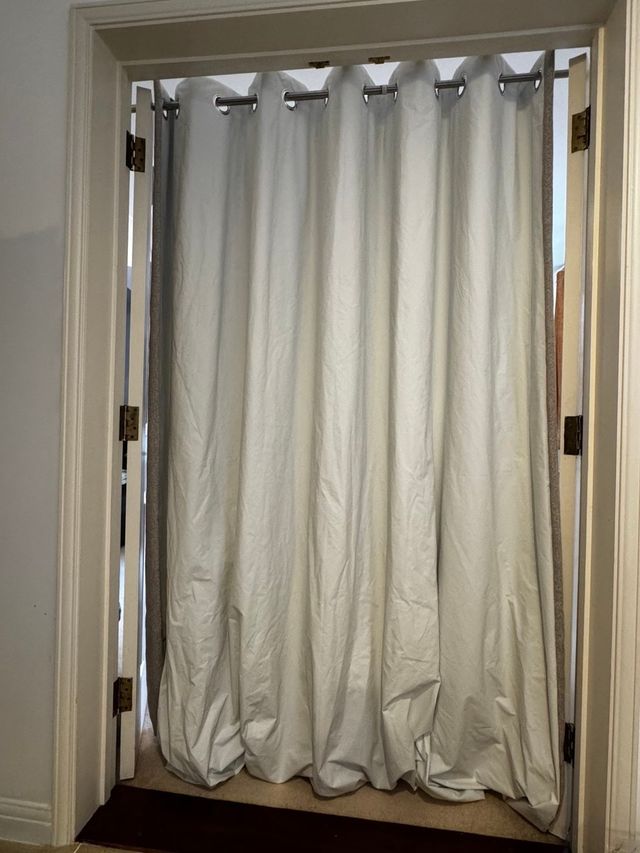 Cream eyelet curtain in a doorway, too long and pooling on the floor