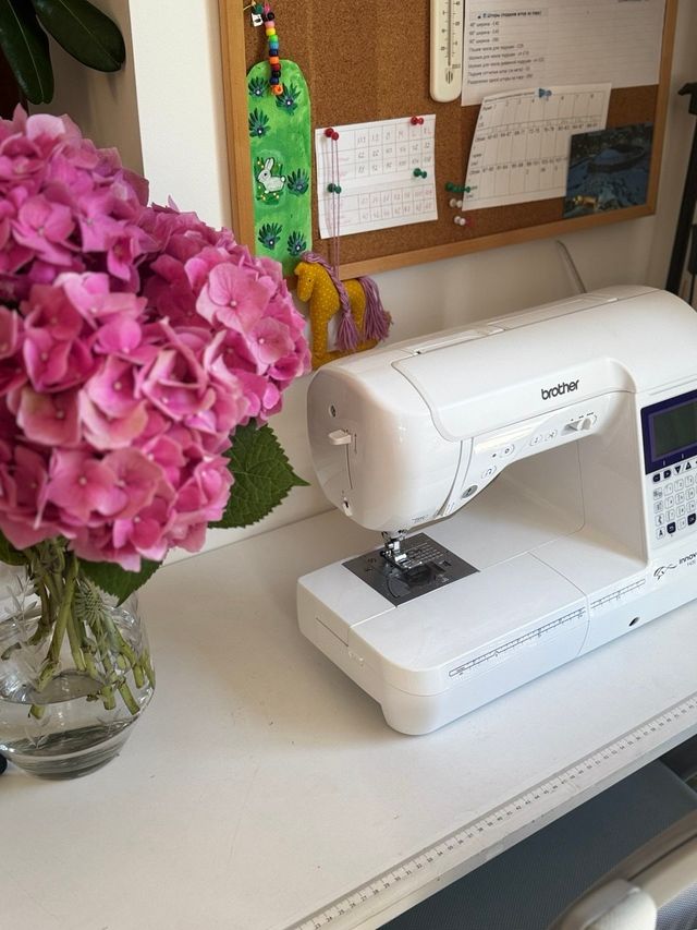 Pink hydrangeas beside the sewing machine and a pinboard of size charts