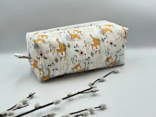 Boxy quilted zip pouch in a fox and deer print beside a sprig of pussy willow