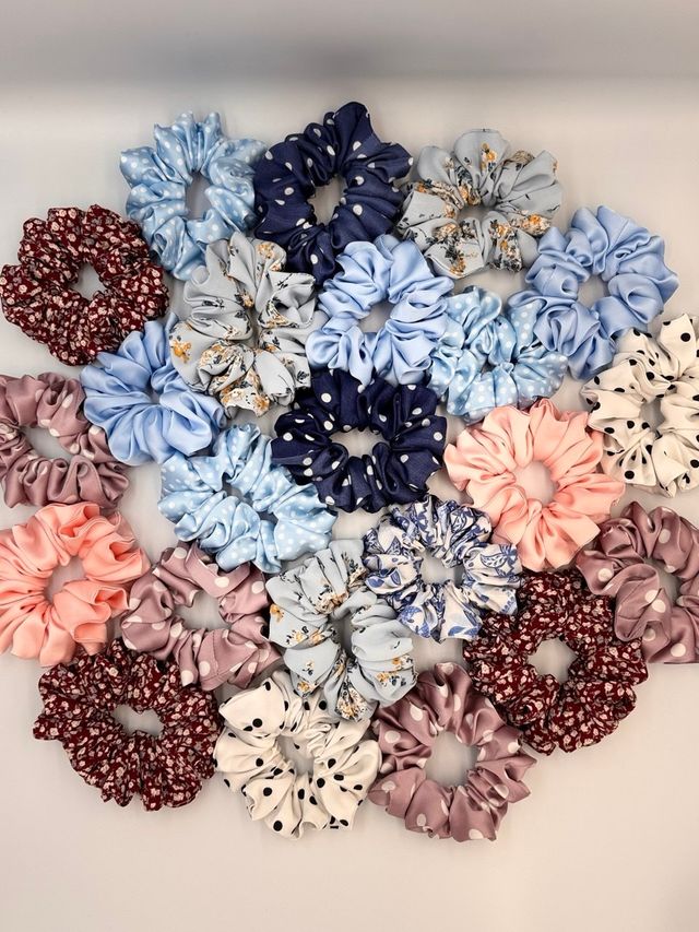 Dozens of scrunchies in florals, polka dots and plain colours laid out together