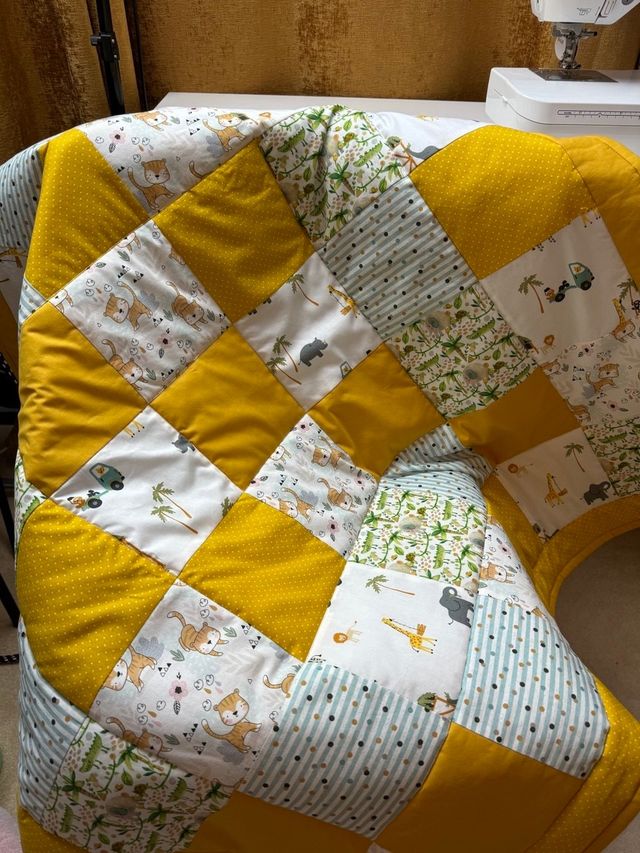 Patchwork quilt in mustard, mint and safari-print squares draped over a chair