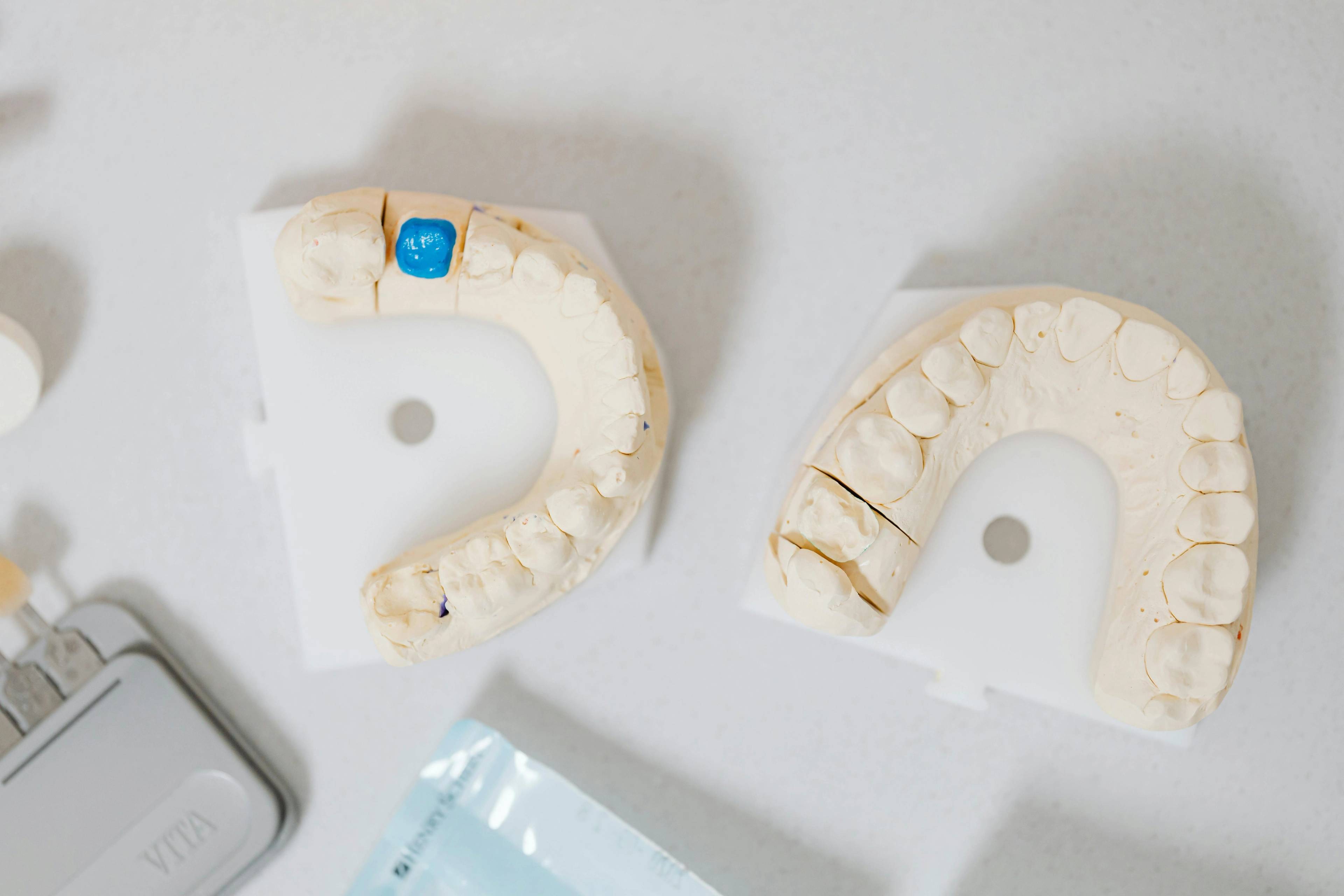 close up image of dental teeth models on white desk surrounded by other dental implements