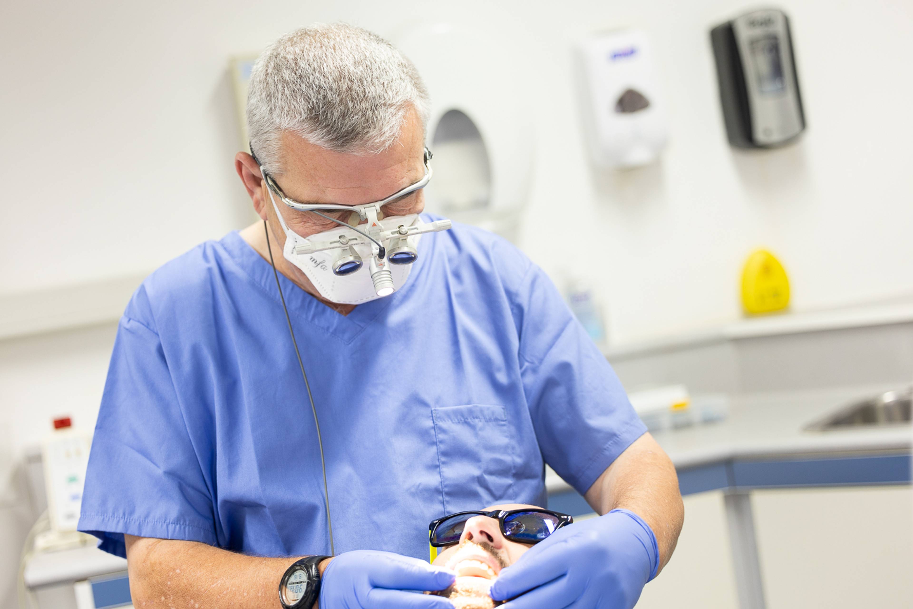 Dentist in blue scrubs examining patient during dental check up