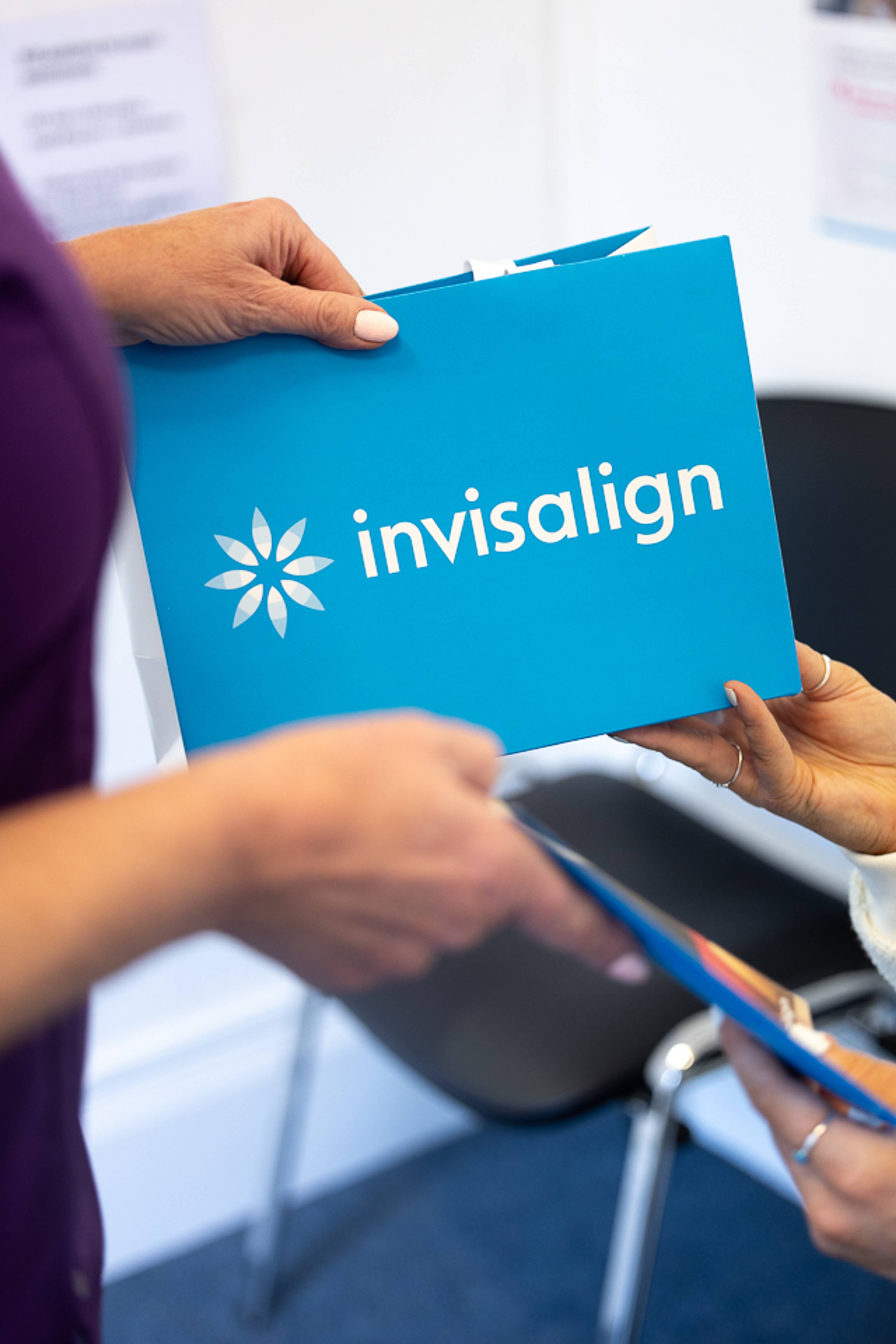 Close up of dental nurse's hands giving a blue Invisalign bag to patient