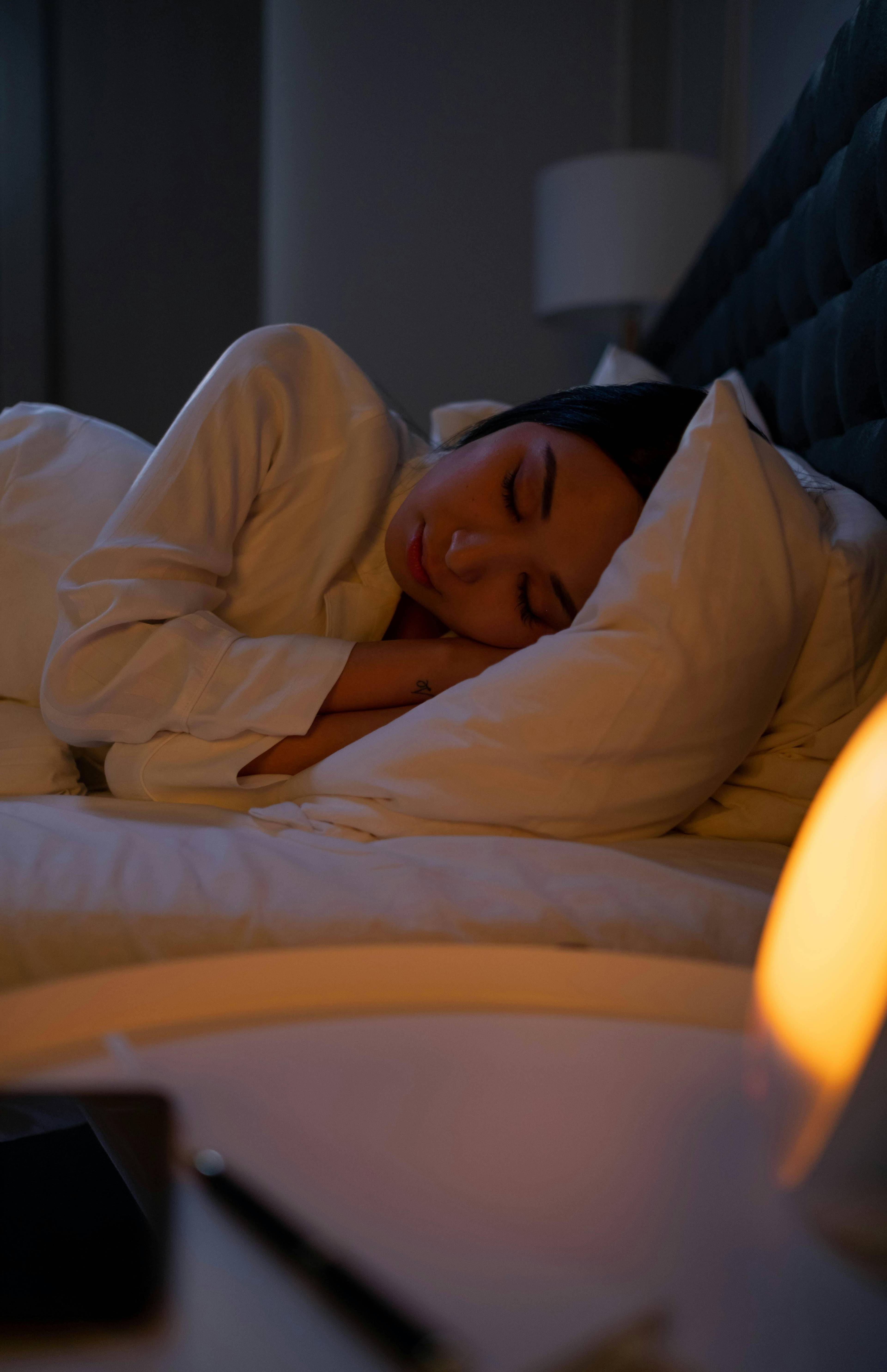 woman sleeping in comfy bed with yellow nightlight on bedside table