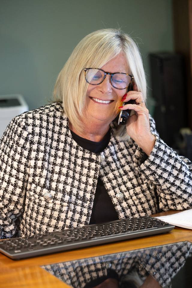 Receptionist in a black and white checked blazer smiling on the phone