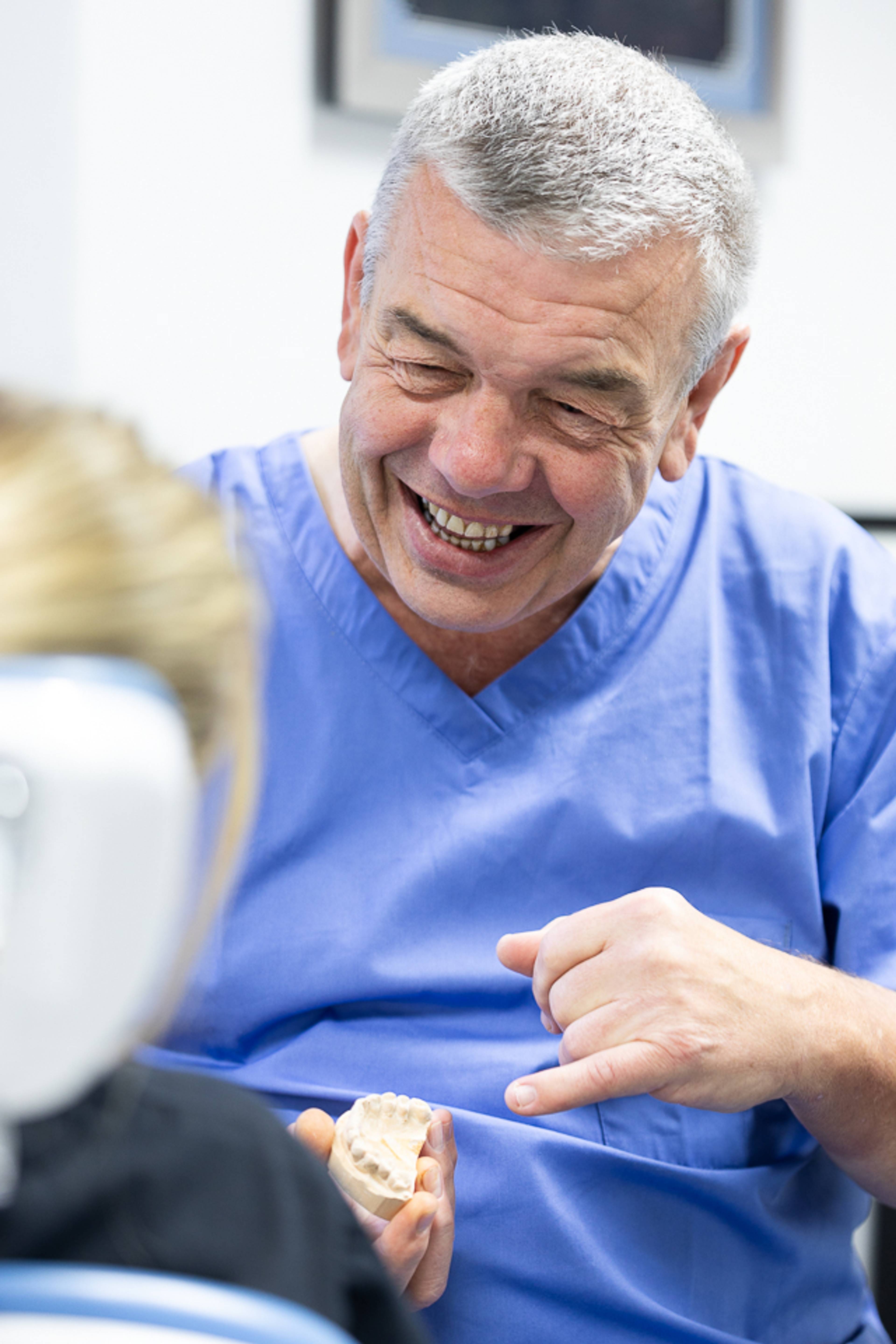 Pontcanna Dental Care dentist pointing at tooth model and smiling at patient