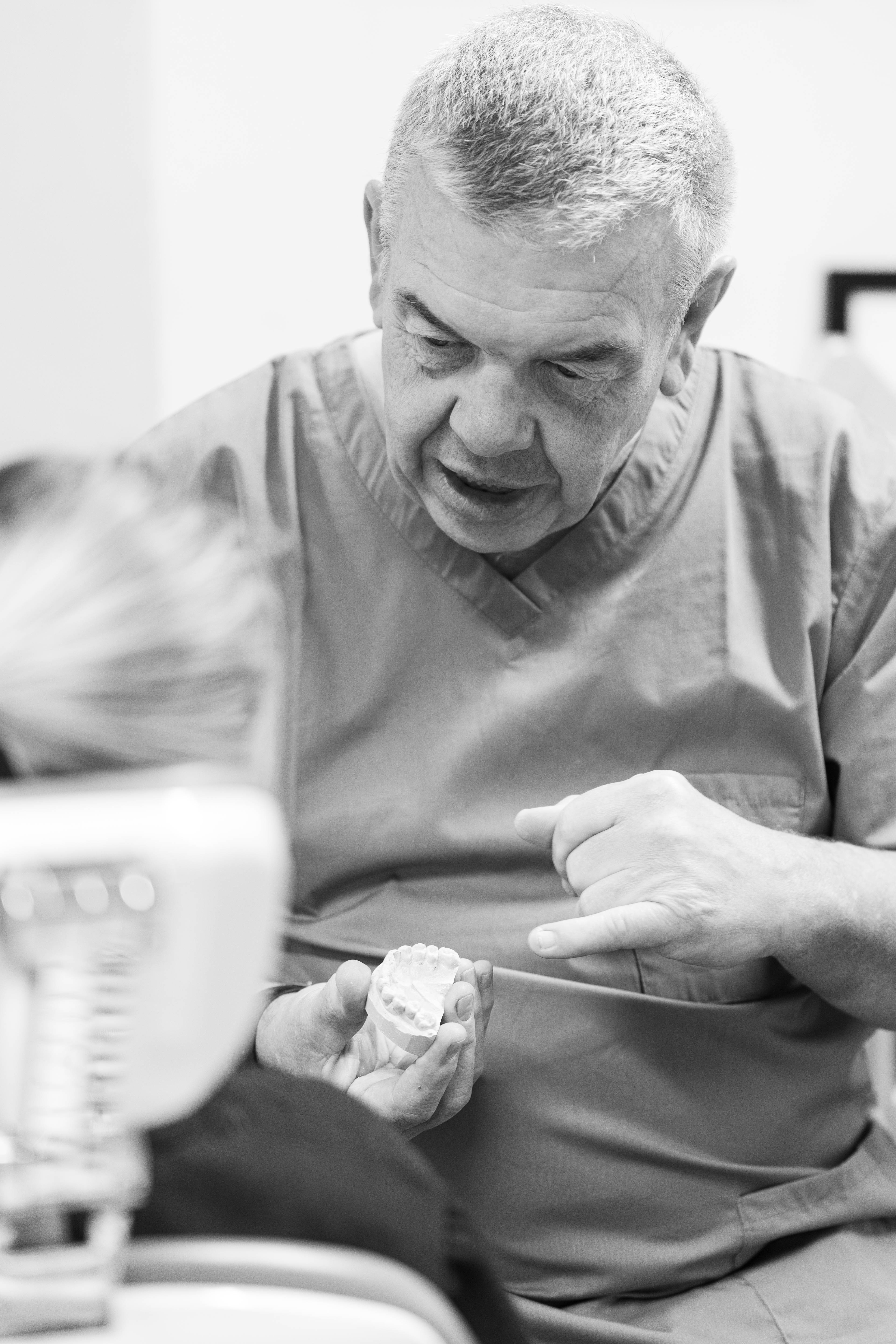 black and white photograph of a dentist showing a patient example of treatment on a model