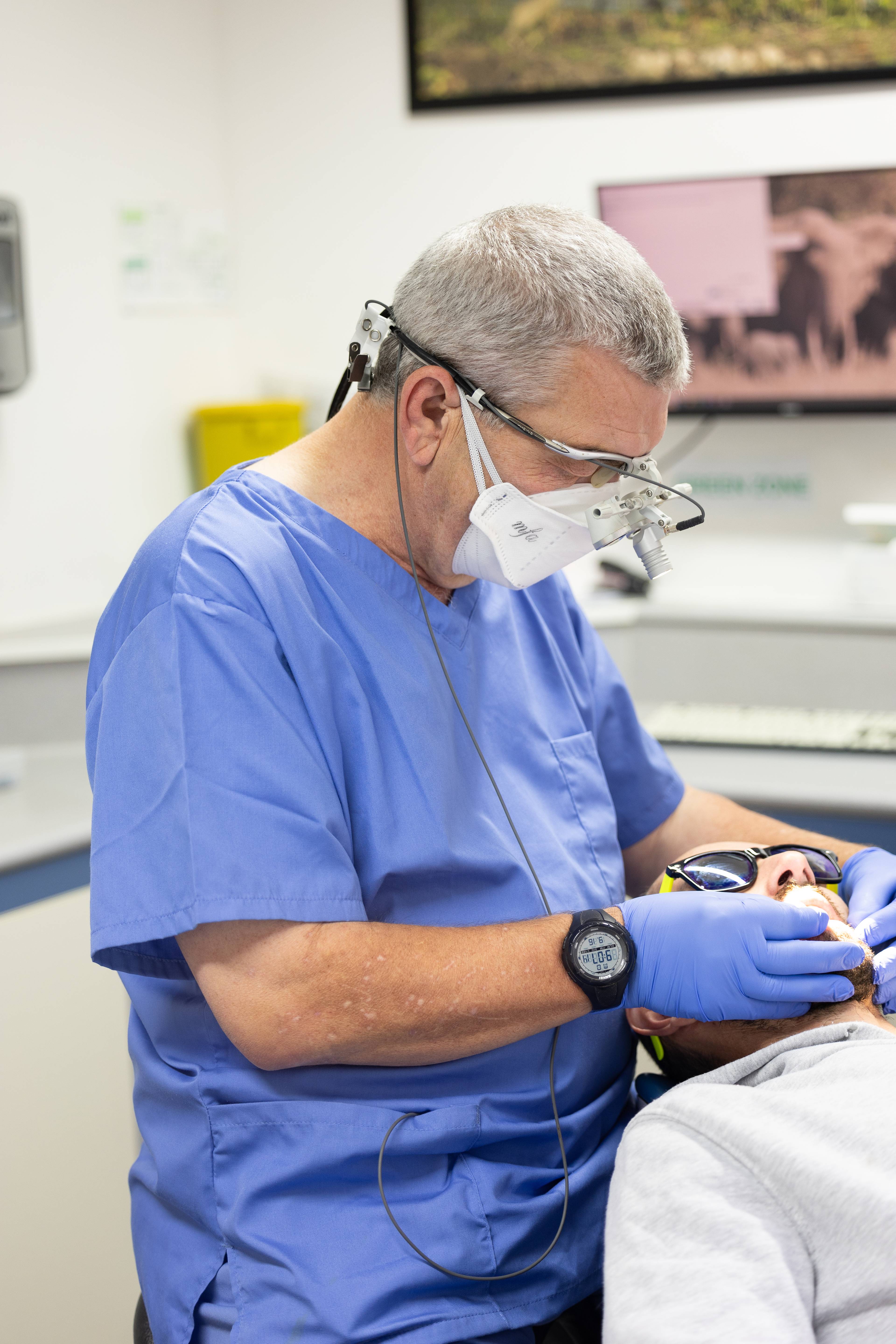 Dentist in blue gloves examining a patients oral health in surgery