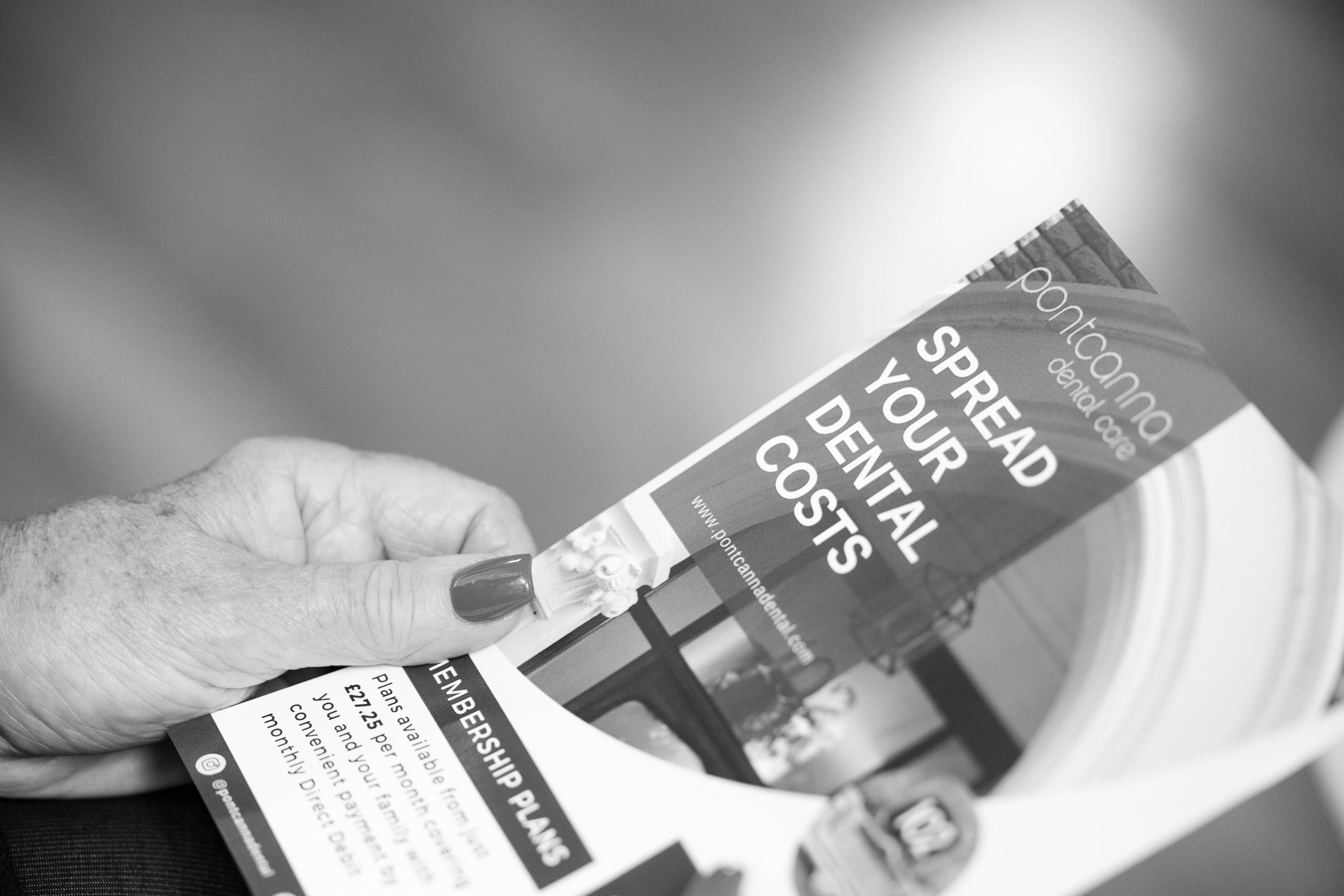 Black and white close up photo of patient holding pricing information leaflet