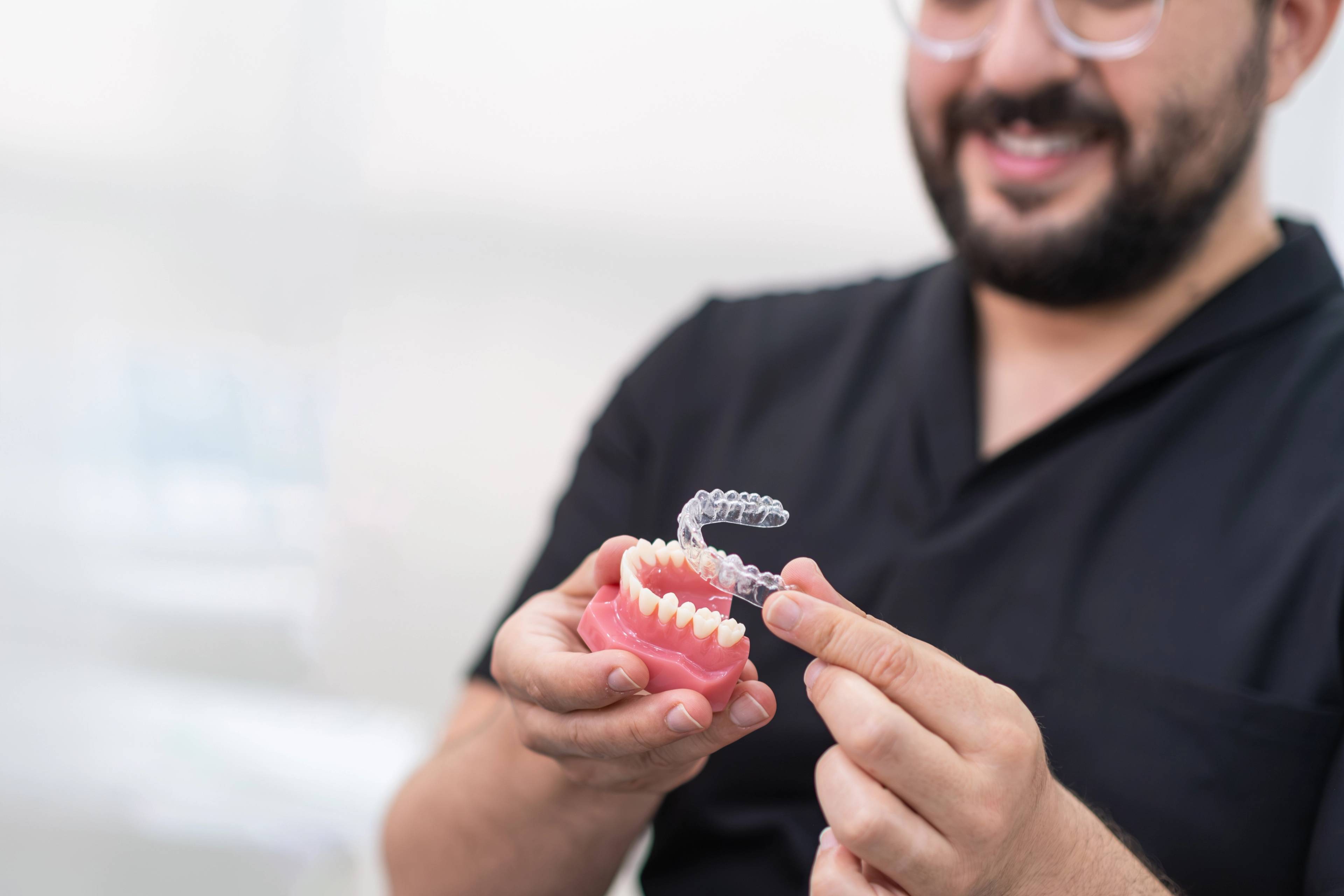 Dentist showing using a plastic teeth model to show how Invisalign aligners fit