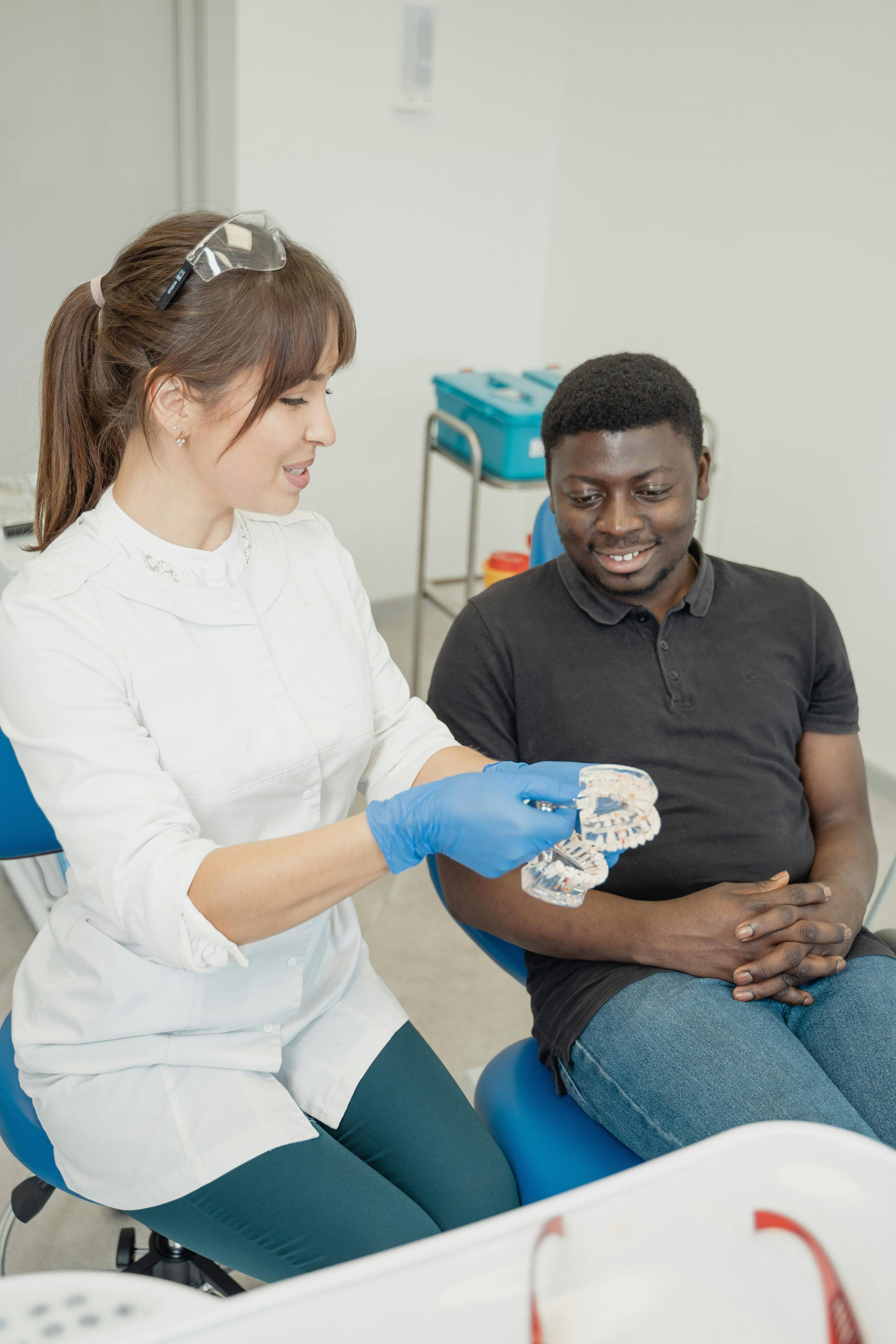 Female dentist showing a young male patient clear plastic mold of teeth
