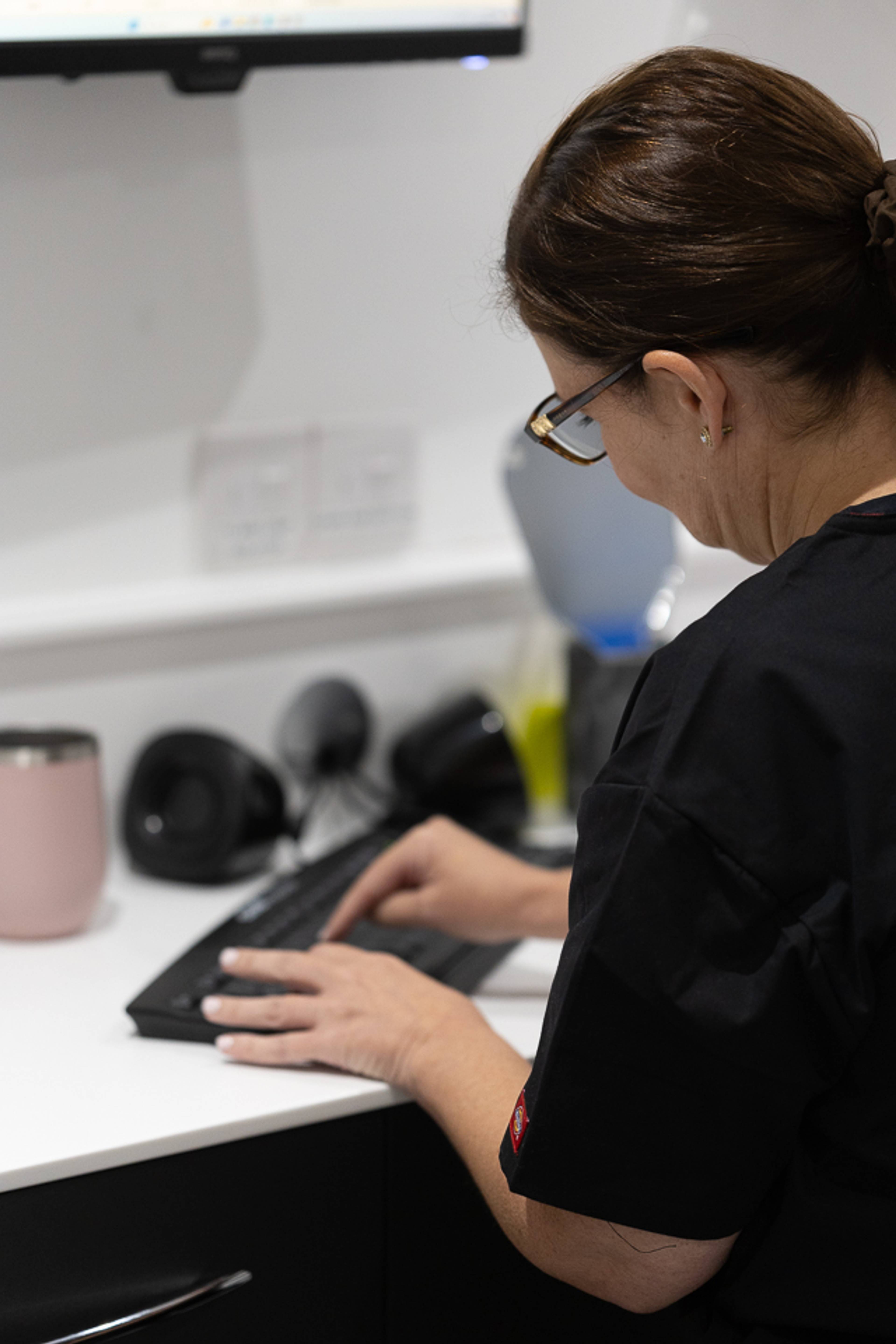 receptionist looking away while sitting at desk and typing on keyboard