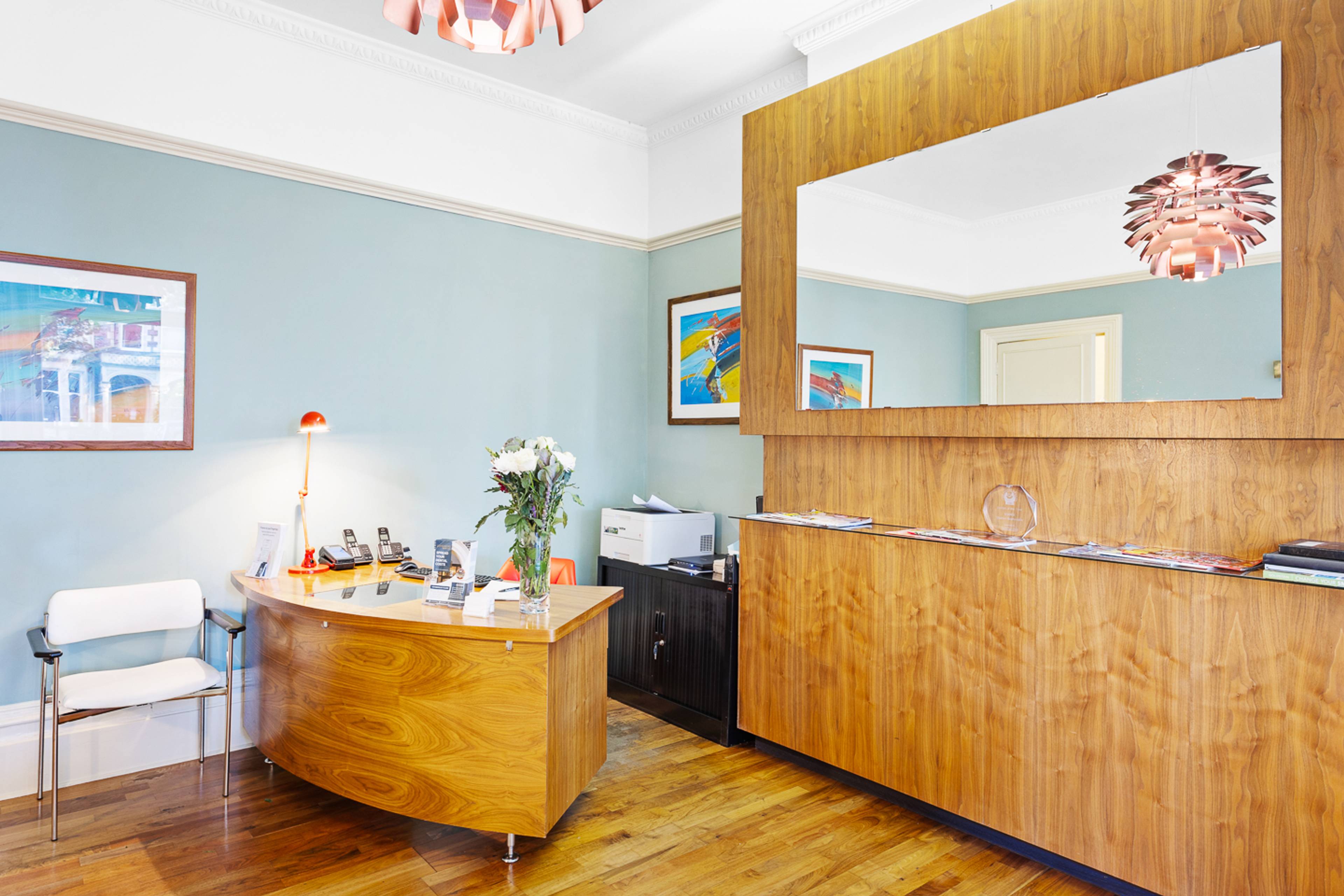 reception desk and waiting area at pontcanna dental care featuring large mirror on wall and bright colours on walls