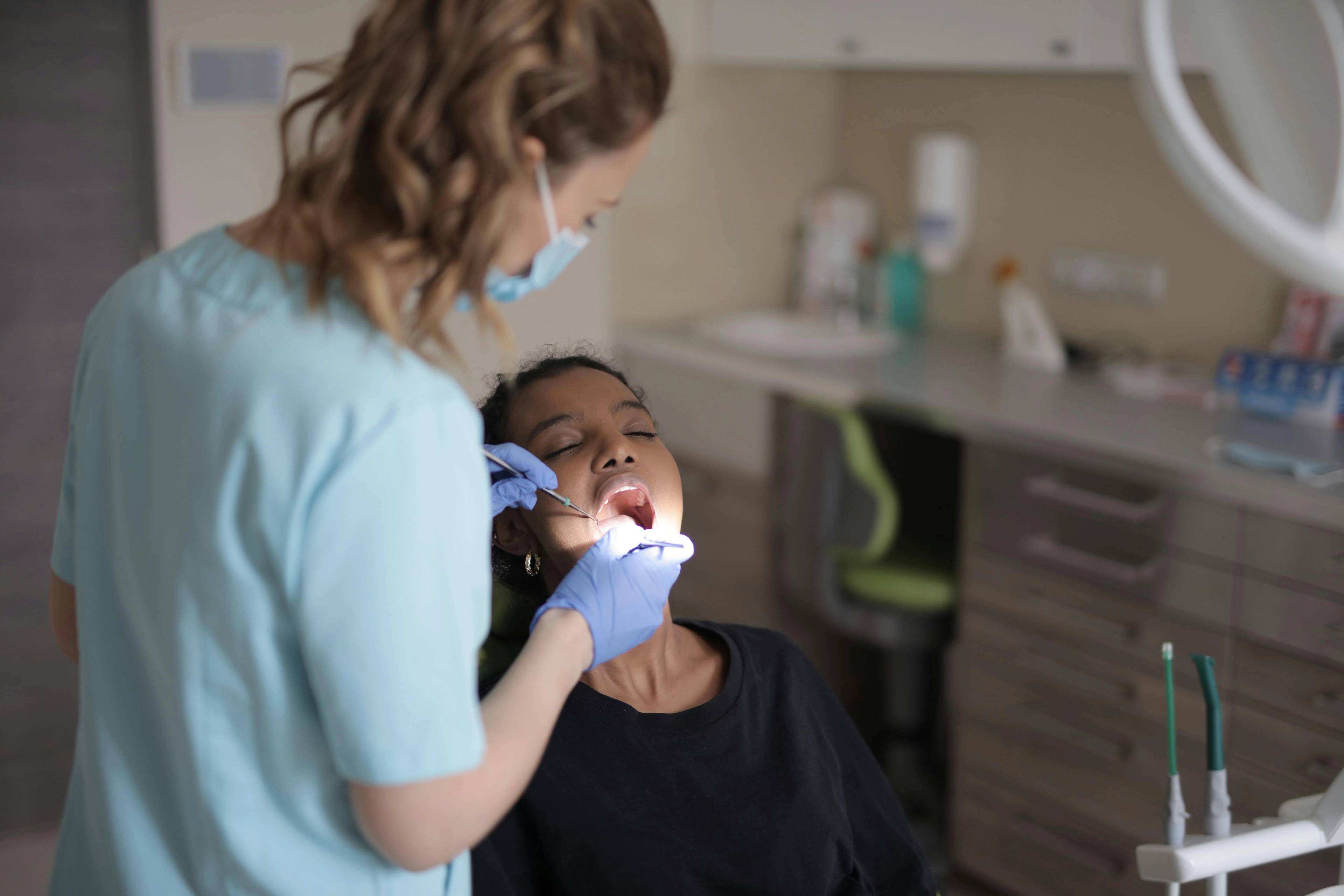 patient undergoing tooth extraction in surgery from dentist wearing blue gloves