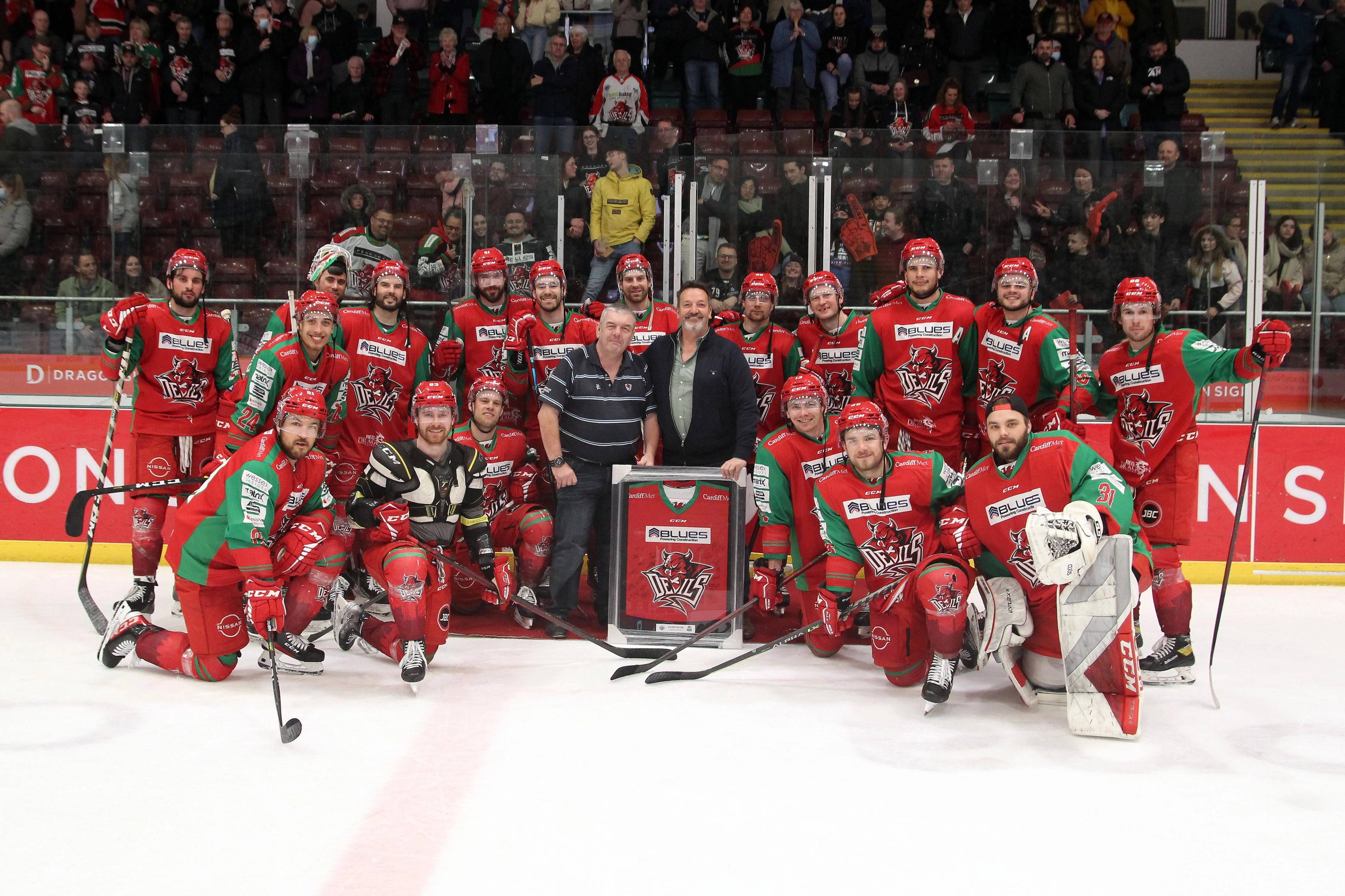Cardiff Devils team all on the ice in red kit with Pontcanna Dental Care dentists holding a team jersey