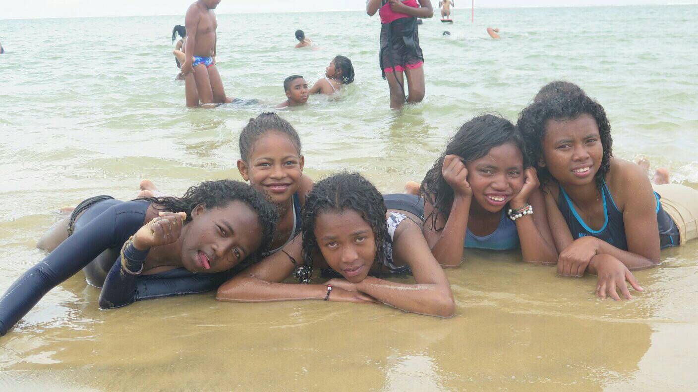 Kinder spielen im Meer und posieren gemeinsam im Wasser.