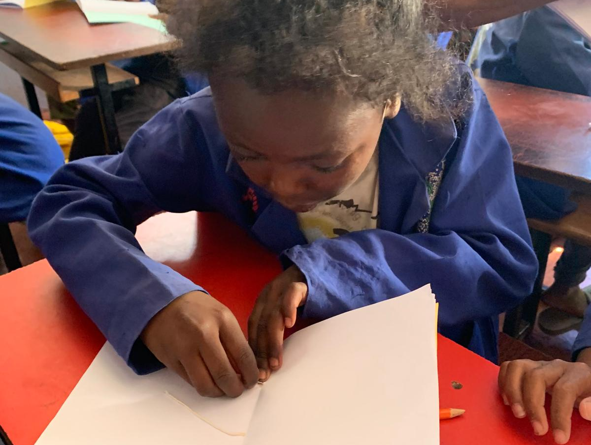 Kinder zeigen ihre selbst gestalteten Hefte im Klassenraum.