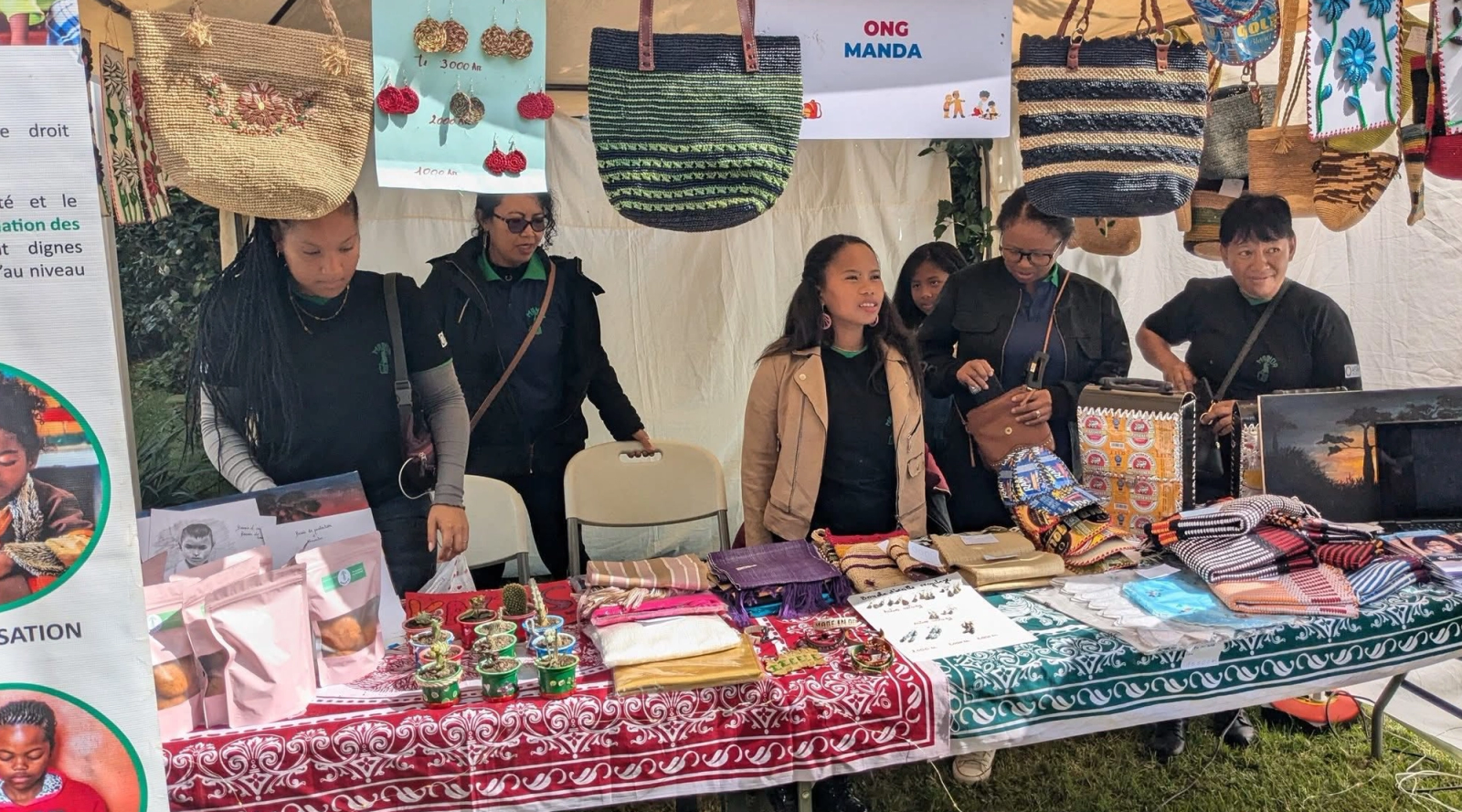 Mitarbeitende präsentieren handgefertigte Taschen und Waren am MANDA-Stand.