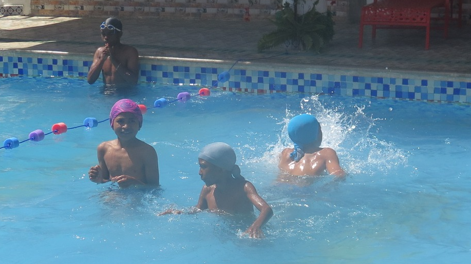Kinder schwimmen gemeinsam in einem Pool.
