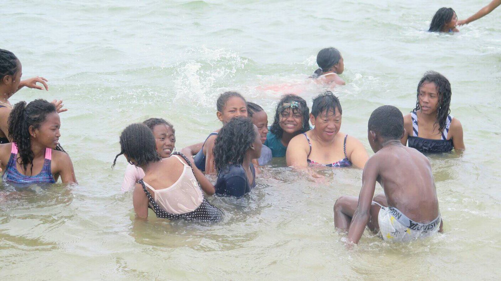 Kinder spielen und schwimmen im Meer.