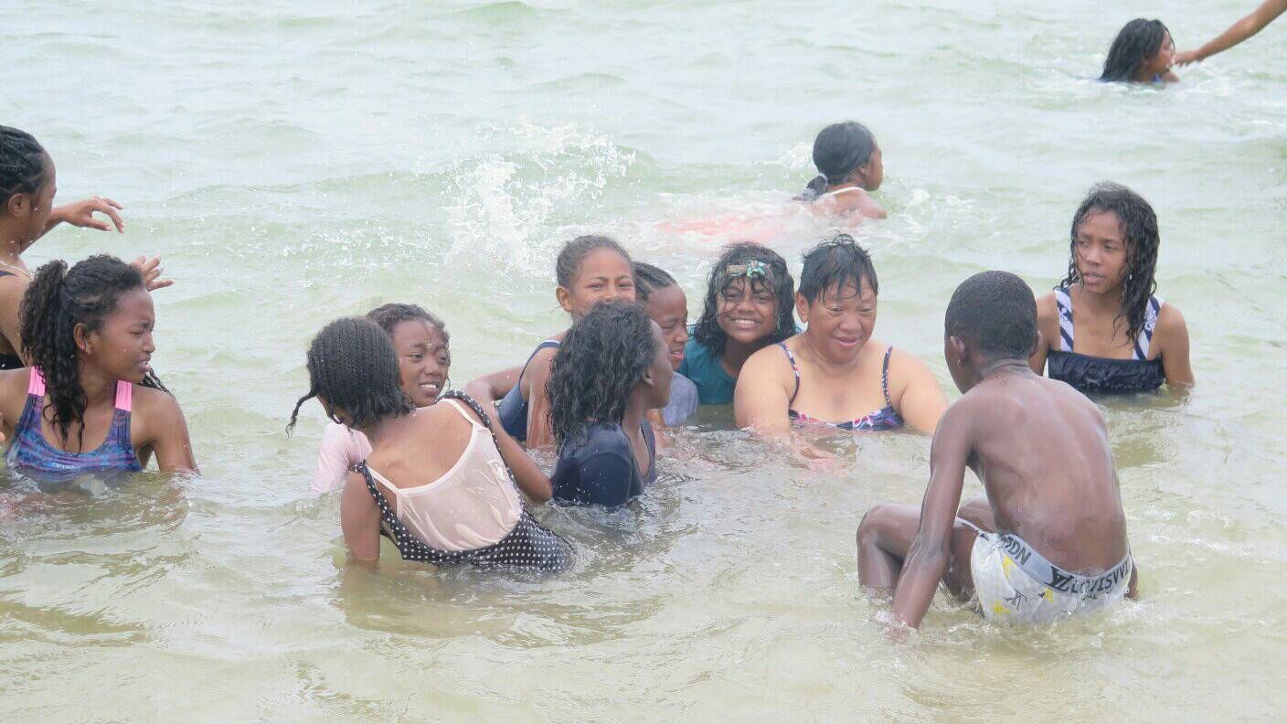 Kinder spielen und schwimmen im Meer.