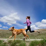 Photo of a woman and a dog running together