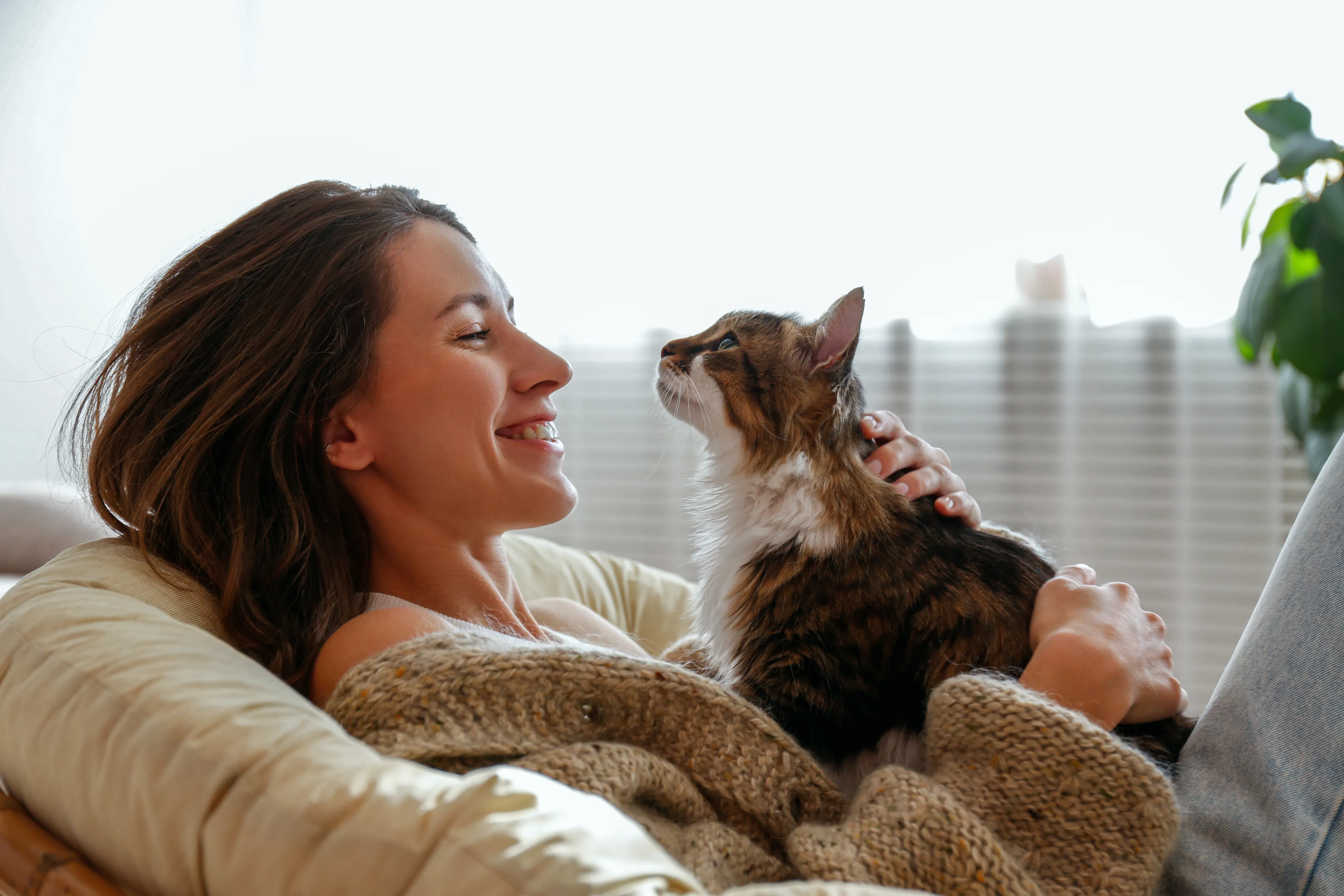 Una mujer tumbada en un sofa abrazando un gato 