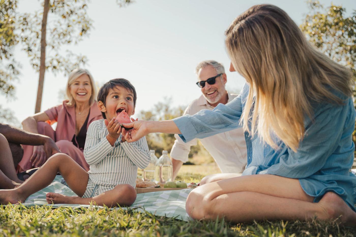 A kid eating watermelon in a family picnic
