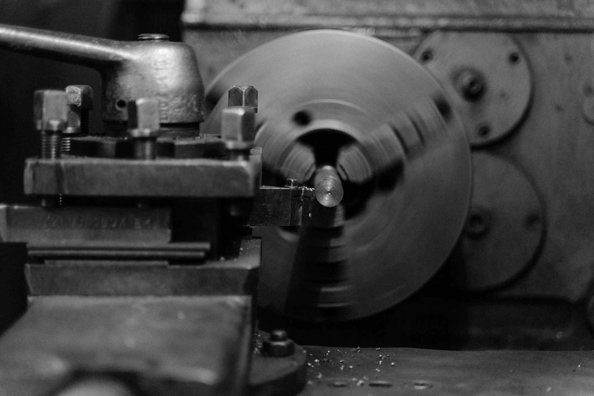 Close-up of a metal lathe spinning a cylindrical workpiece in a workshop