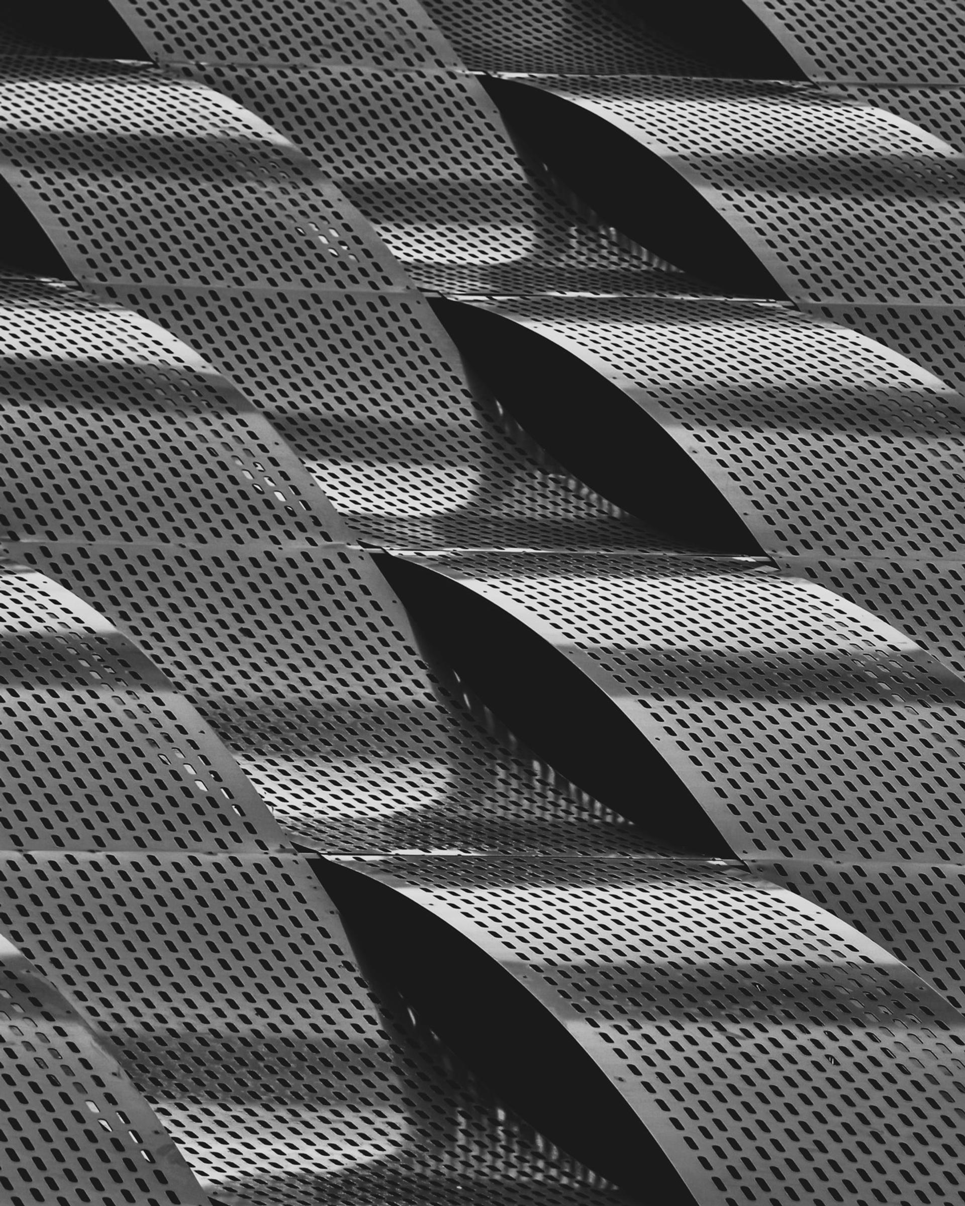 Abstract pattern of curved perforated metal panels in black and white