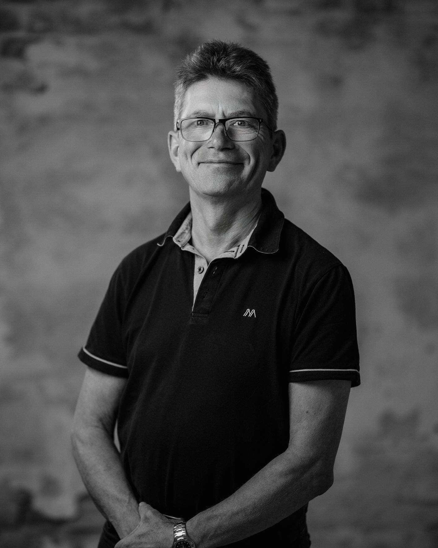 Black-and-white portrait of a middle-aged man in glasses, blazer, and turtleneck