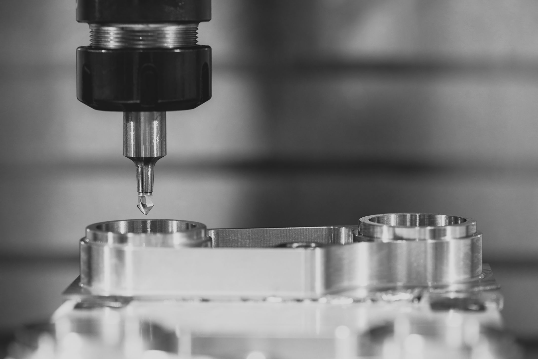 Close-up of a CNC machine tool head above a metal workpiece in a workshop