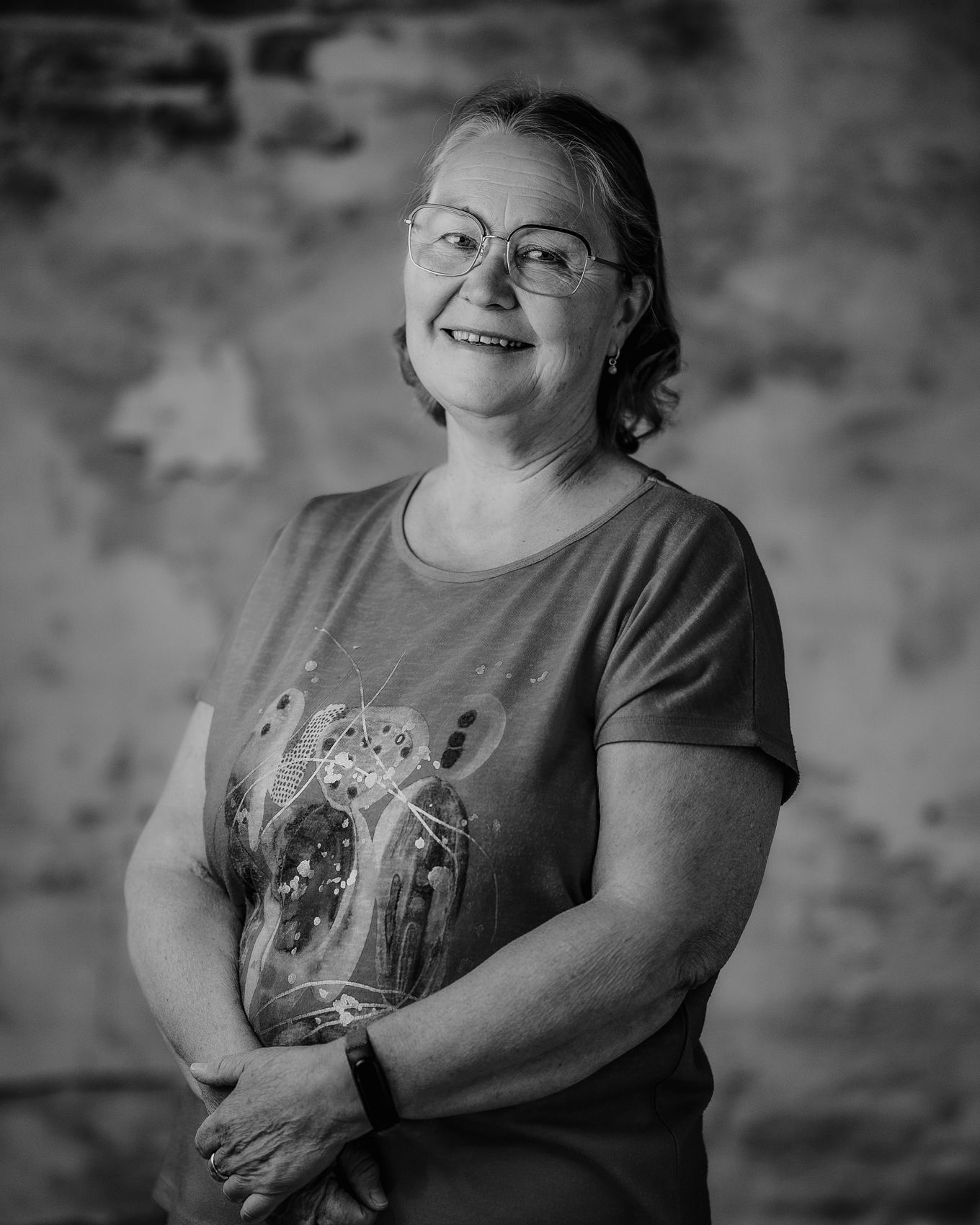 Black-and-white portrait of a middle-aged person with glasses, smiling slightlyIngrid Juul
