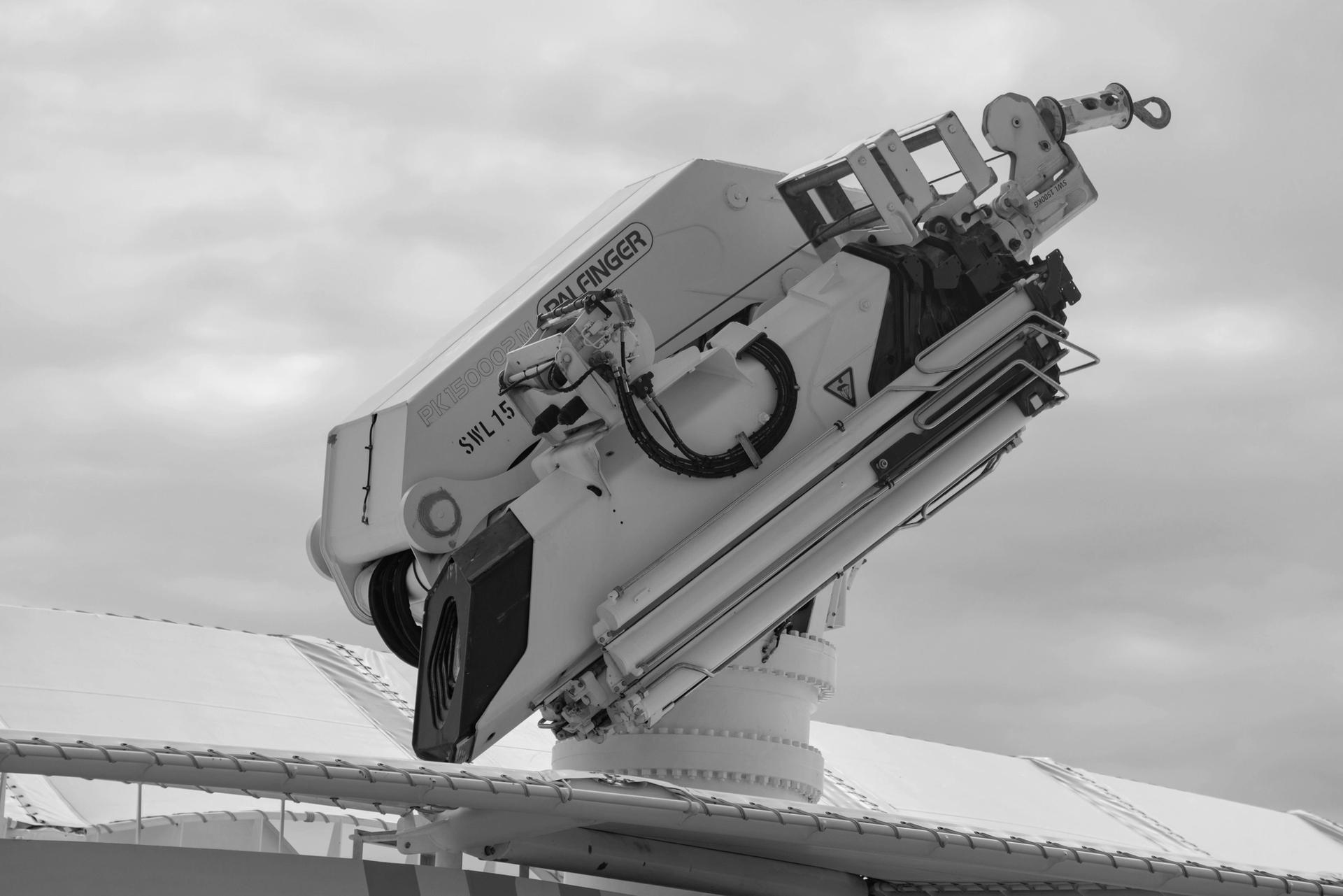 Close-up of a mounted industrial crane arm against a cloudy sky