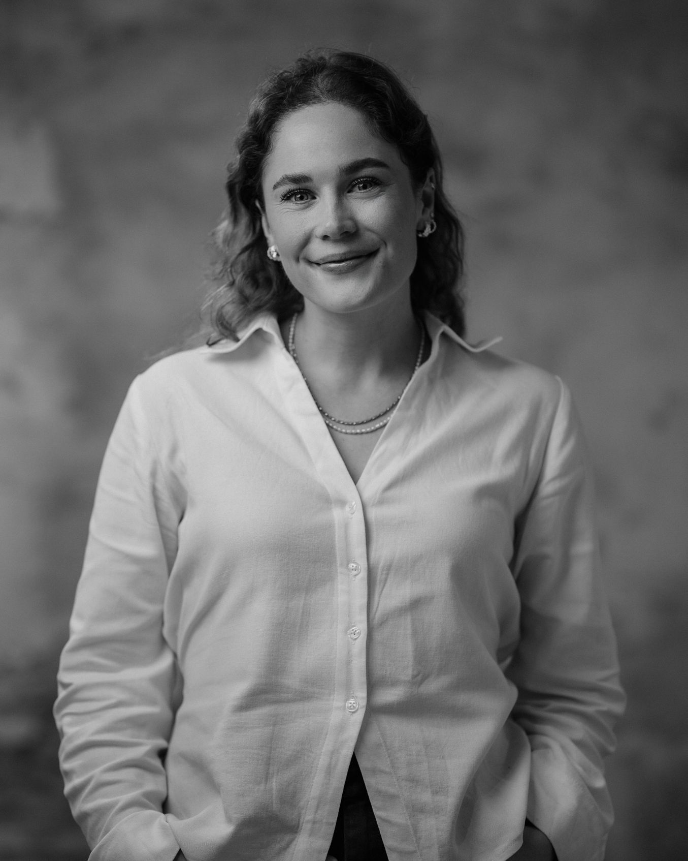 Black-and-white portrait of a smiling woman in a blazer standing outdoors
