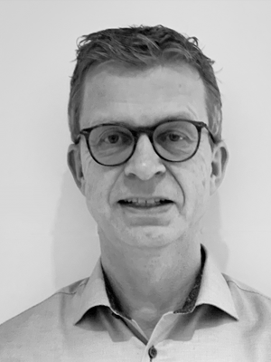 Black-and-white headshot of a middle-aged man wearing glasses and a collared shirt