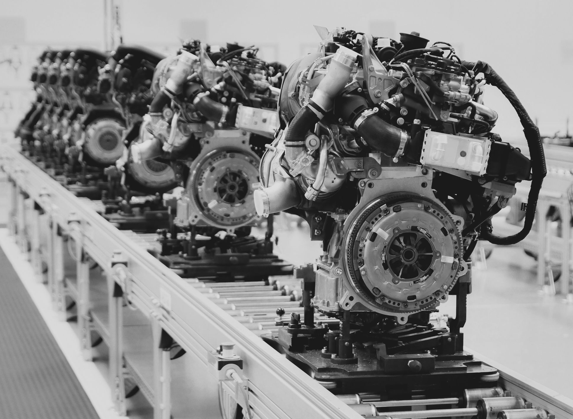Row of car engines on an assembly line in a factory, shown in black and white