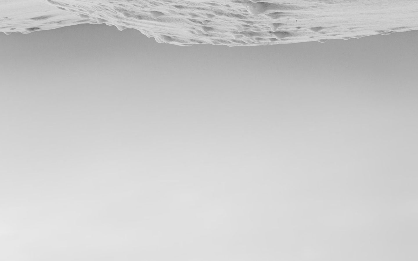 Minimalist view of rippled sand at top fading into empty gray sky below