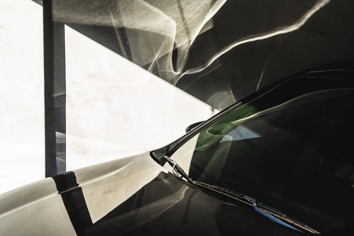 Light reflects off the hood of a car and onto a wall making a busy pattern