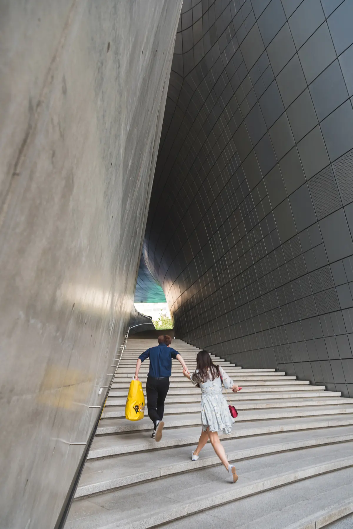 A couple holding hands runs up a stairwell at Dongdaemun Design Plaza in Seoul.